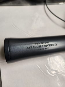 A microphone with 'Property of Syracuse University' engraved on it